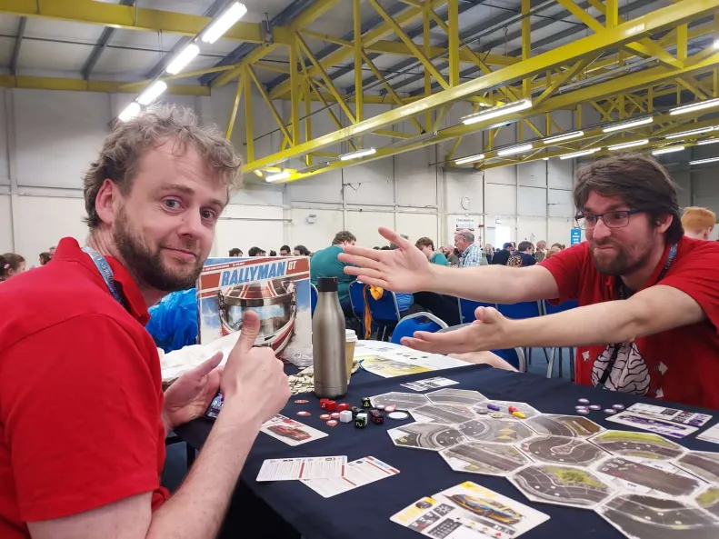 Iain is on the left of the photo with two thumbs up. Jamie is on the right displaying his exasperation with Iain's win. Rallyman GT is on the table between them