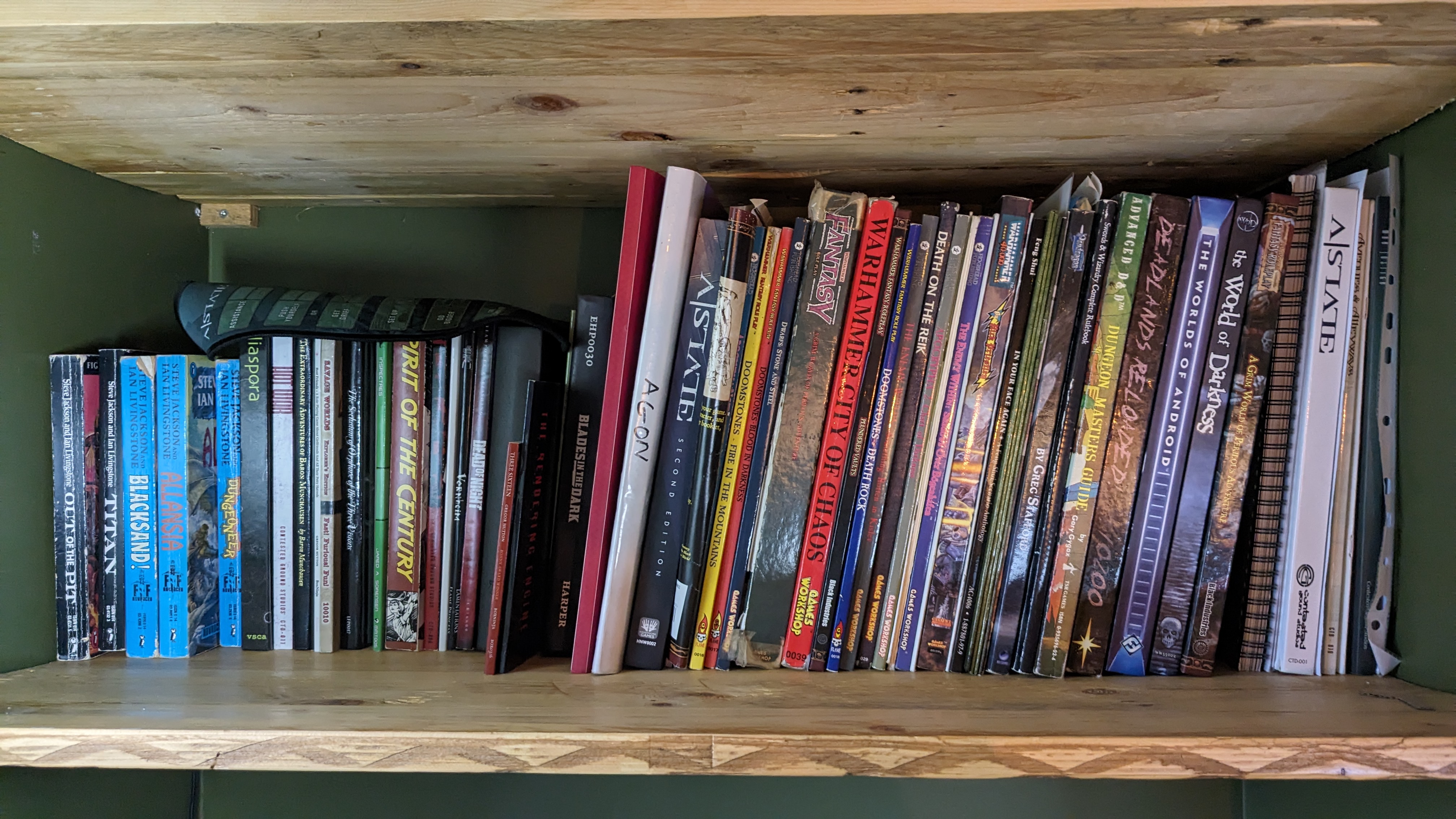 My shelf of RPGs containing loads of titles such as Blades in the Dark, King Arthur Pendragon, Agon, Hot War, too many to list.