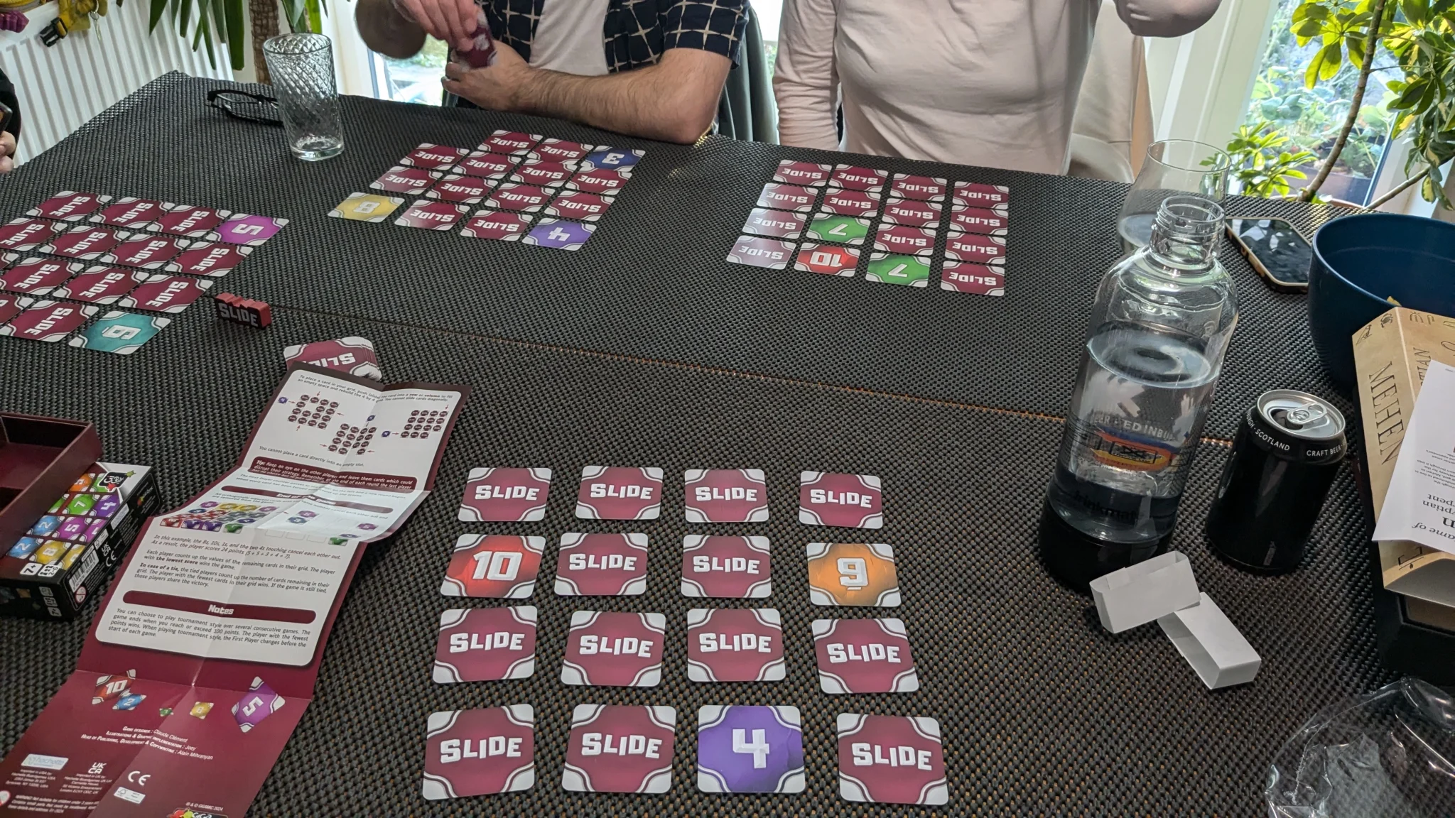 A game of Slide in progress. 4 people are playing. In front of me is a 4x4 grid. If the grid is read left to right, top to bottom then 2 cards are revealed. A 9 in position 8 and a 4 in position 15